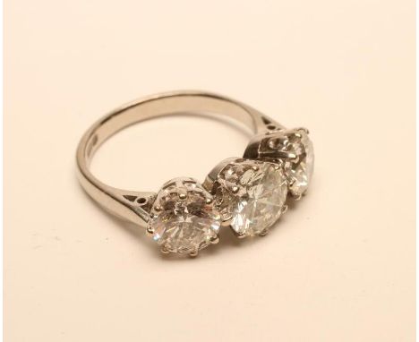 A THREE STONE DIAMOND RING, the central brilliant cut stone of approximately 1.55cts claw set and flanked by two similar smal