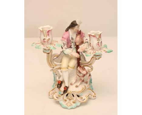 A DERBY PORCELAIN FIGURAL TWO BRANCH CANDELABRUM, c.1770, modelled as young piping shepherd wearing a plumed hat, pink jacket