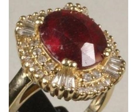 A RUBY AND DIAMOND CLUSTER RING, the oval facet cut ruby claw set to a border pave set with numerous small round brilliant cu