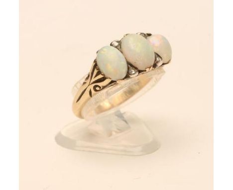 A LATE VICTORIAN OPAL RING, the three cabochon polished stones with rose cut diamond points between reeded shoulders and a pl