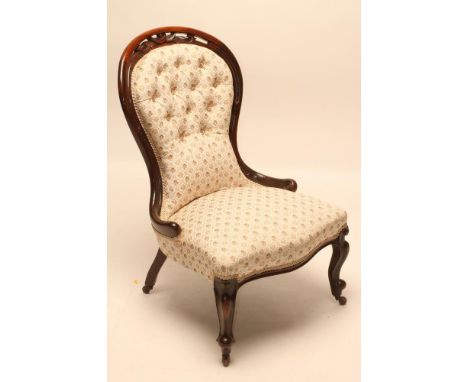 A VICTORIAN WALNUT FRAMED NURSING CHAIR of spoonback form button upholstered in a floral ivory weave, the channelled framed b