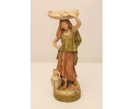 A ROYAL DUX FIGURE, early 20th century, modelled as a young female in Middle Eastern costume holding a flat basket on her hea