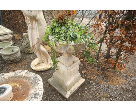 A painted concrete garden urn raised on three tier plinth used as a planter