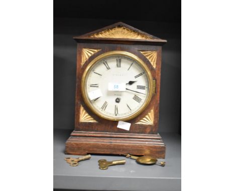 An early 20th century oak cased mantel clock, of architectural form with carved and gilded surmount and spandrels enclosing t