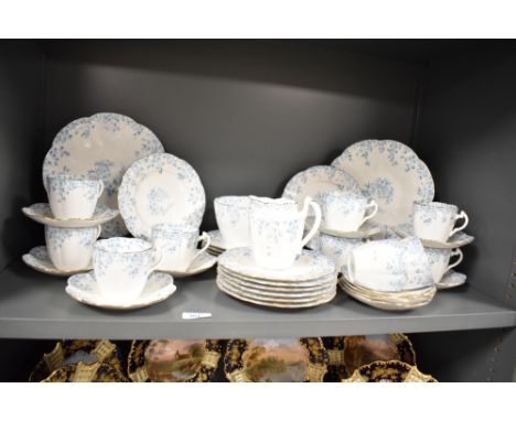 A Foley fine bone china part dinner service, decorated with gilt edging and blue floral patterns on a white ground, makers ma