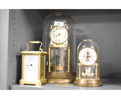 A 20th century brass and glass 400 day anniversary clock, with torsion pendulum, sold together with a similar smaller clock a