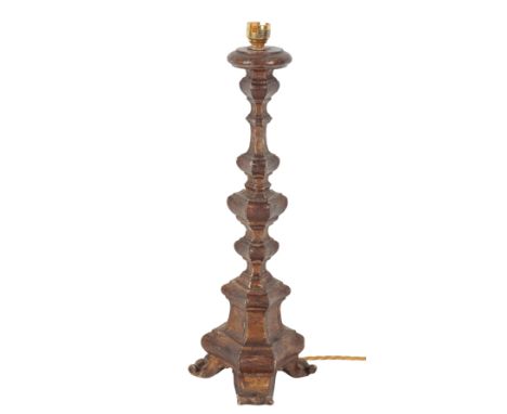 AN 18TH CENTURY GILTWOOD CANDLESTICK OF BAROQUE DESIGN with circular sconce, stepped triangular stem, on scrolled toes, 49cm 