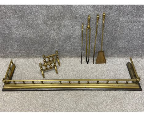 A collection of 19th century brass fireside items to include a fender with turned spindles and finials on a square moulded ba