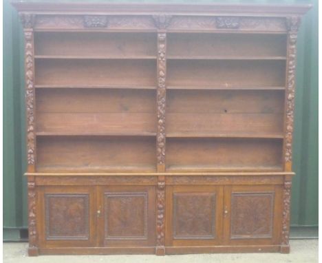 Large Victorian carved oak library bookcase, raised back with moulded cornice, mask and scroll carved frieze and six adjustab