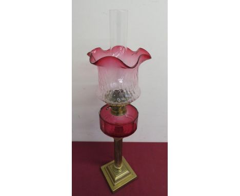 Victorian brass column oil lamp, cranberry glass reservoir and similar shade on stepped square base (H74cm) 