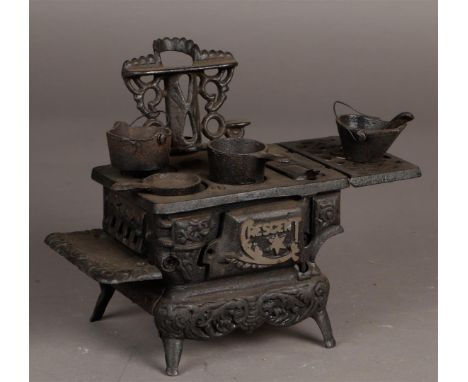 Een vintage gietijzeren halve maan "Crescent" miniatuur speelgoedkachel met accessoires. 