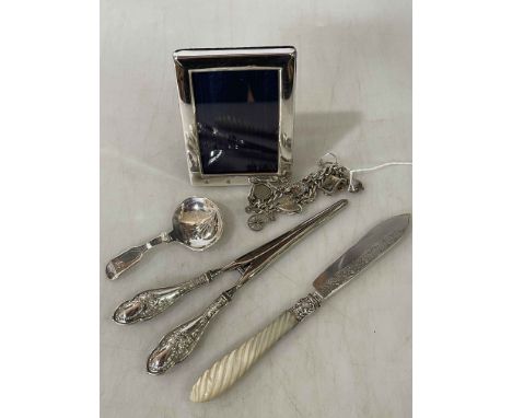 Silver charm bracelet, silver and mother of pearl butter knife, small silver frame, glove stretchers and plated caddy spoon (