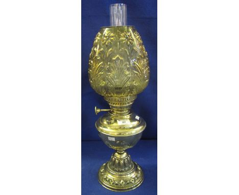 Brass oil lamp with brass reservoir and repousse brass pedestal base, moulded glass shade with clear chimney. 58cm high appro