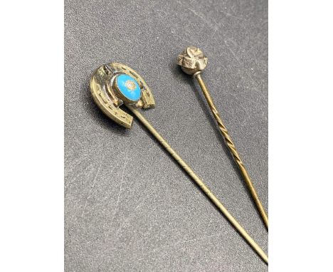 A gold topped stick pin with dent and horse shoe stick pin