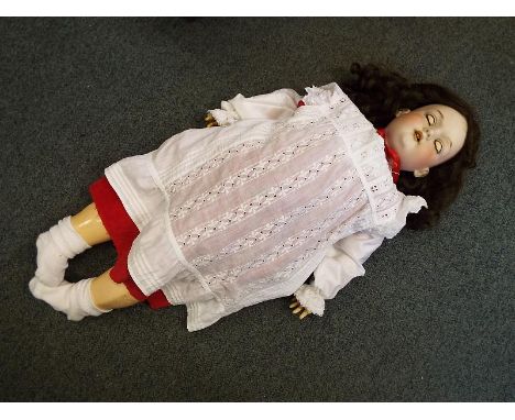 An early 20th century Armand Marseille 390 bisque headed doll on composite body, fully jointed limbs, brown wig, sleeping eye