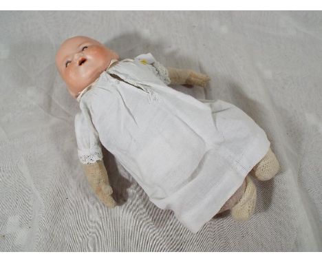 A Armand Marseille baby doll with bisque head, material jointed body with sleeping eyes, open mouth displaying teeth. Marked 