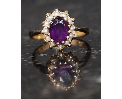 An antique 9ct gold cluster ring set with central purple stone surrounded by seed pearls marked 9ct. Weight 2.5g. Size K.5

F