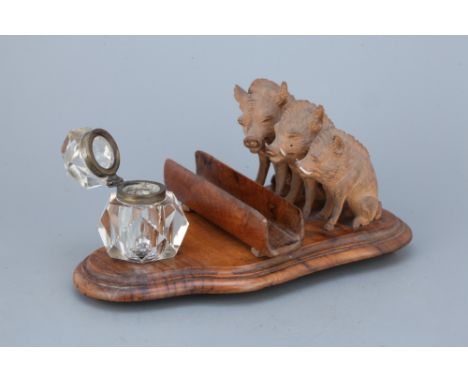 unmarked, base possibly polished olive wood, with cut glass inkwell, pen rest, and three well-carved boar, 19cm long