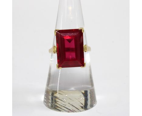 18ct gold ruby dress ring, the emerald cut ruby in a six claw setting, inner band stamped 18ct.