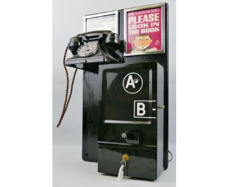 A telephone box coin-operated A and B button machine, the black enamelled case mounted on a black painted wooden board with b