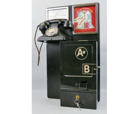 A telephone box coin-operated A and B button machine, the black enamelled case mounted on a black painted wooden board with b