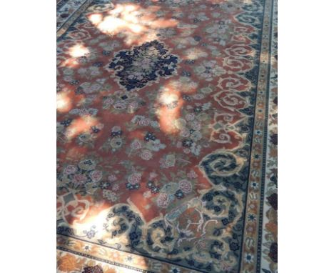 A Belgium Oriental style carpet, on pink ground with blue central lozenge and borders, 370cm x 273cm.