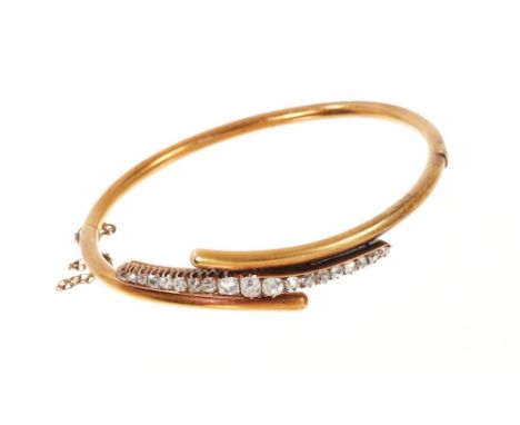 Late 19th Century diamond hinged bangle with a line of graduated cushion shape old cut diamonds in claw setting on 14ct gold 