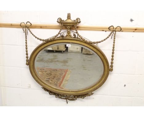 Edwardian Adam-style gilt framed wall mirror, with oval bevelled plate below Grecian urn and swag surmount and conforming apr