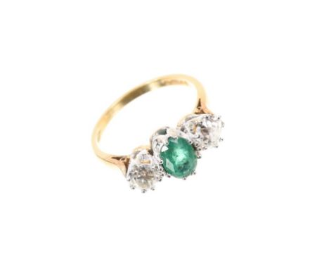 Emerald and diamond three stone ring with an oval mixed cut emerald flanked by two old cut diamonds estimated to weigh approx