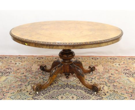 Victorian figured walnut oval loo table, the hinged top with foliate carved edge raised on bulbous column and quadruped sport