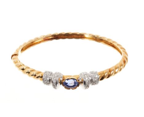 18ct gold tanzanite and diamond hinged bangle with an oval mixed cut tanzanite flanked by pavé set diamonds in 18ct white and