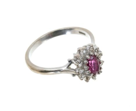 Ruby and diamond cluster ring with an oval mixed cut ruby surrounded by 12 brilliant cut diamonds in claw setting on 18ct whi