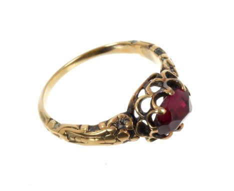 Antique garnet single stone ring with a mixed cut garnet in claw setting with cast foliate shoulders on gold shank. Finger si