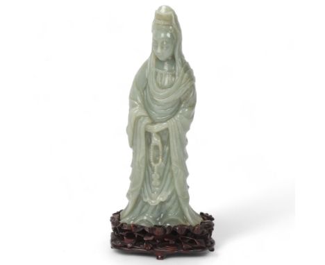 A Chinese carved green jade figure of Guan Yin on carved hardwood stand, overall height 32cm, provenance: from a local deceas