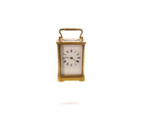 A brass French carriage clock, having black Roman numerals on white enamel face, key present