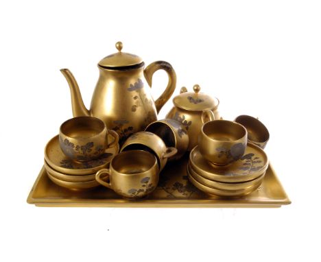 A Japanese lacquered tea set, having gold ground and decorated with floral design, together with a larger lacquered tray