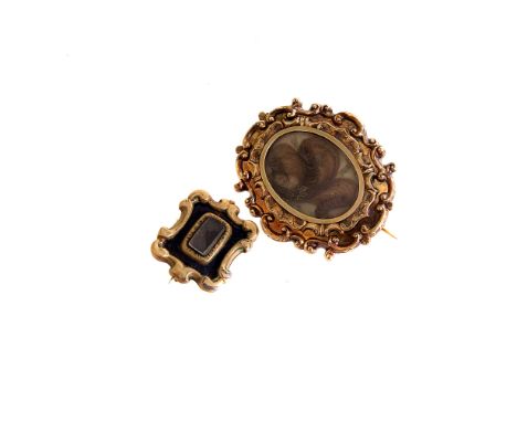 A 19th century mourning brooch, the ornate mount with glazed panel of hair, together with another mourning brooch with black 