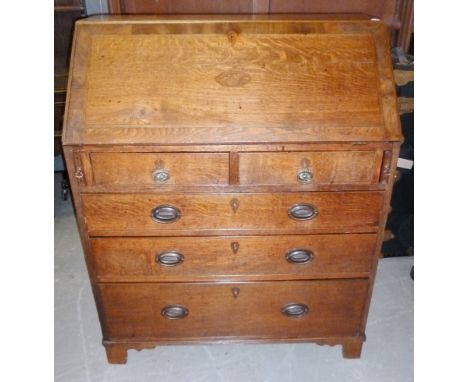 A George III oak bureau, with mahogany cross banded fall enclosing a fitted interior, surmounting a two over three drawer bas