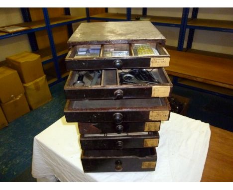 A vintage wooden watch repairers cabinet, containing many back removal tools, pocket watch hands and more