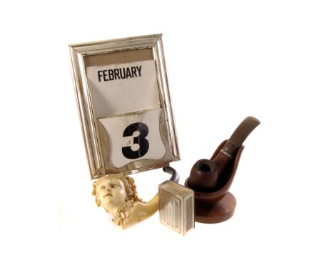 A Gentleman's Lot: comprising of a Meerschaum pipe, another smoking pipe, a perpetual date calendar, a pipe rack and a white 