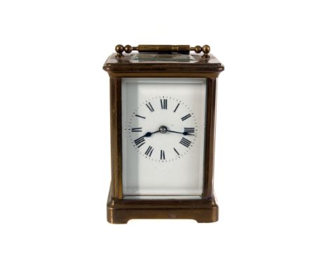 A brass a glazed carriage time piece, having black Roman numerals on white enamel face, with bevelled glace showing face and 