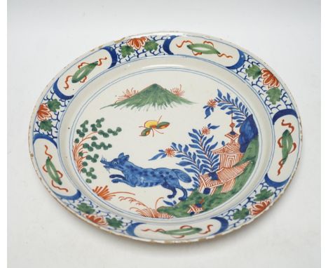 An 18th century Delft dish, the centre painted with a wolf, a bee and a pavilion, 35cmNot cracked, repaired or restored but n