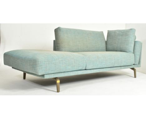 A Contemporary British Design upholstered chaise lounge settee. The sofa having a single side and shorter back rest over a cu