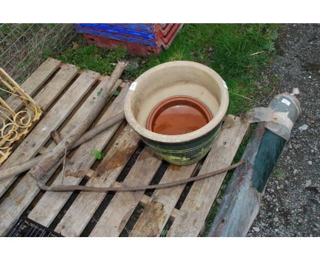 A glazed planter, tarpaulin and a broken scythe.
