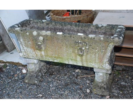 A concrete planter having lion masks in relief to the front and rear and standing on two recumbent lion supports, 3' wide x 1