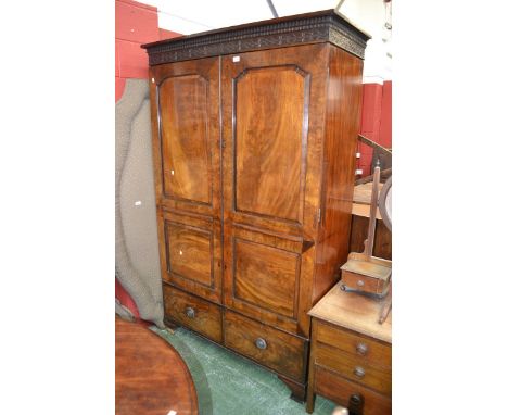 An early 19th century flame mahogany double wardrobe, fluted congé cornice, blind fretworked frieze, fielded panel doors, two