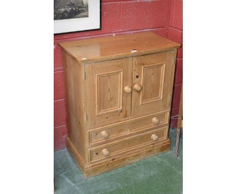 A pine side cabinet, two panel doors enclosing shelving over two long drawers, plinth base. 92cm high x 77.5cm wide.