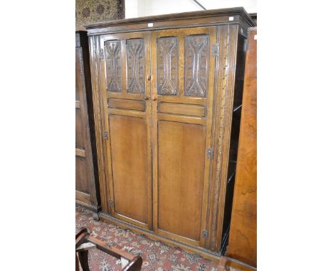 A 20th century oak double wardrobe, stepped cornice, two craved panel doors, shaped apron.