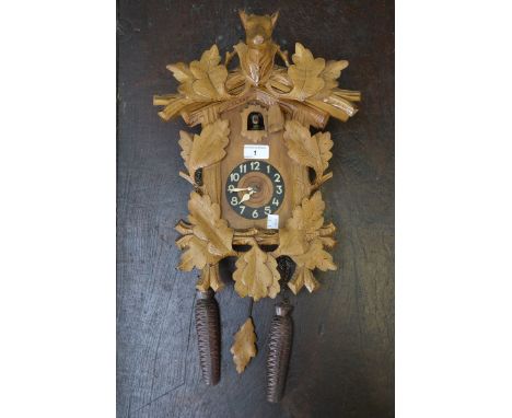 A cased wooden cuckoo clock with weights and pendulum