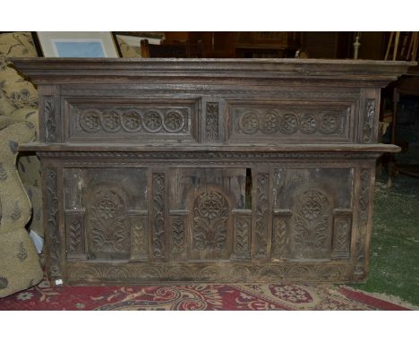 A carved oak overmantel, stepped cornice, small shelf over flora and demi-lune carved panelling